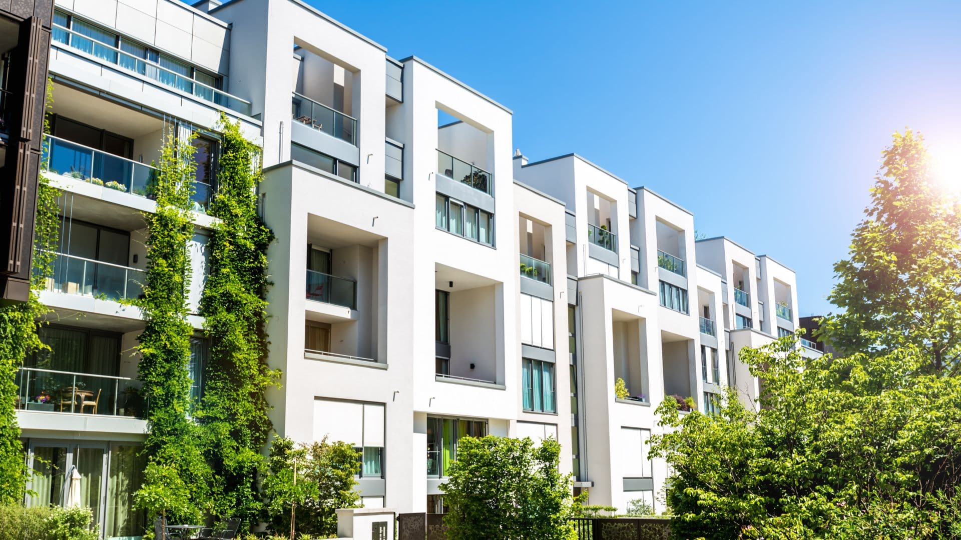 A row of modern low-rise buildings with planted balconies.